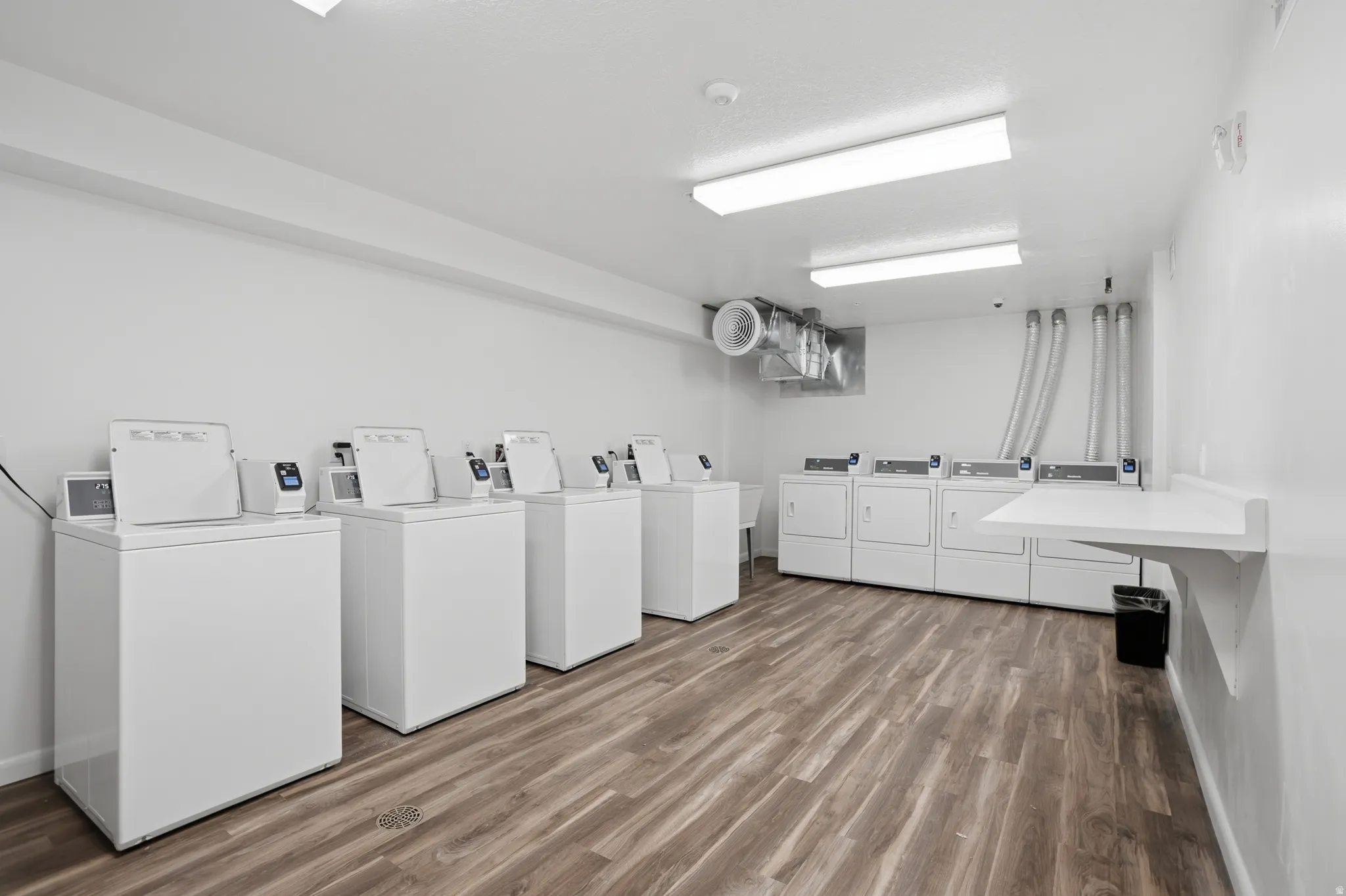 Dedicated laundry area featuring multiple white top-load washing machines and front-load dryers
