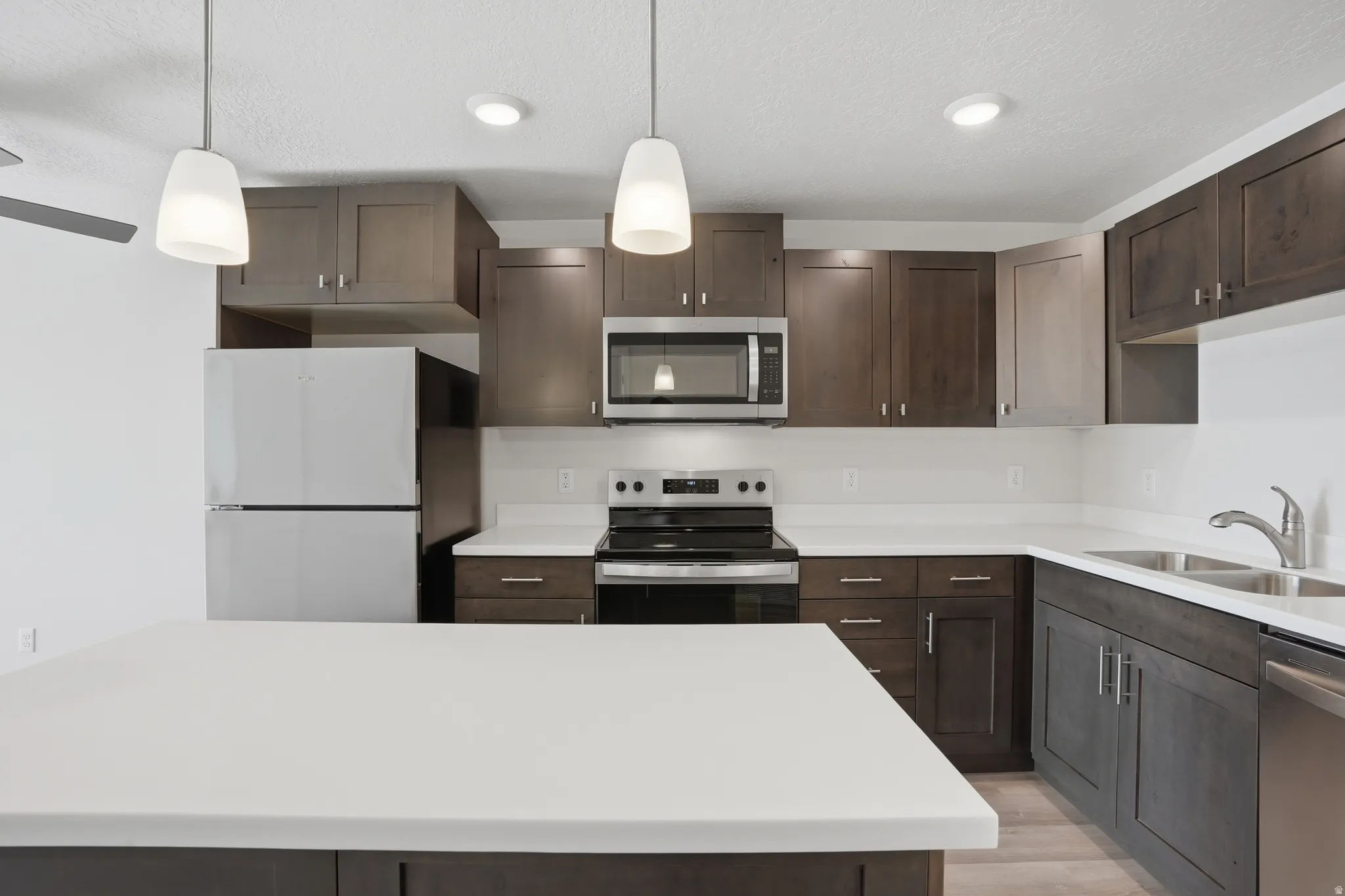 Open-concept kitchen and living area featuring a central island with white quartz countertops, beautiful cabinetry, and stainless steel appliances