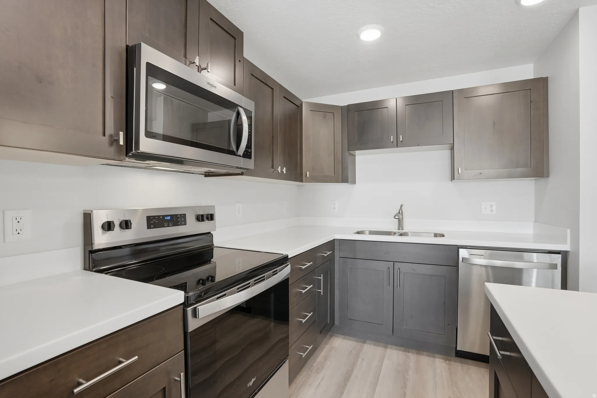 Open-concept kitchen and living area featuring a central island with white quartz countertops, beautiful cabinetry, and stainless steel appliances