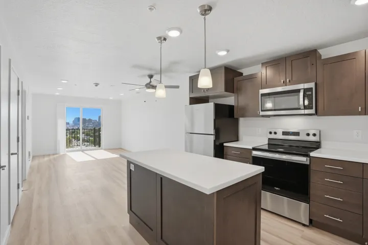 Open-concept kitchen and living area featuring a central island with white quartz countertops, beautiful cabinetry, and stainless steel appliances