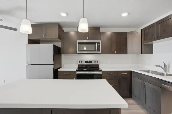 Open-concept kitchen and living area featuring a central island with white quartz countertops, beautiful cabinetry, and stainless steel appliances