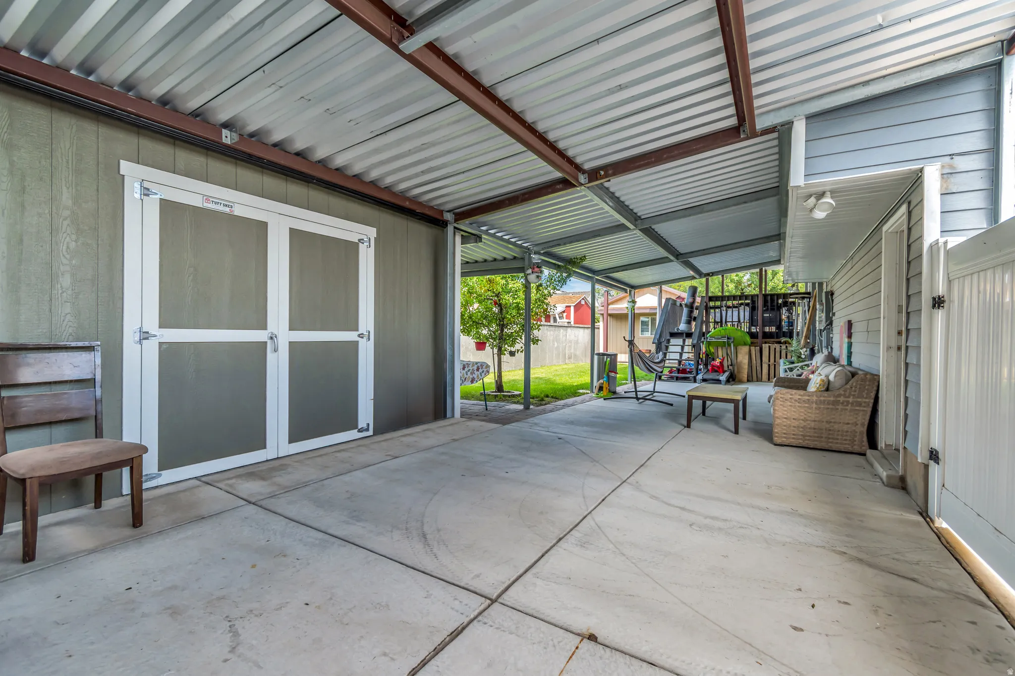 Covered concrete patio area featuring a corrugated metal roof structure