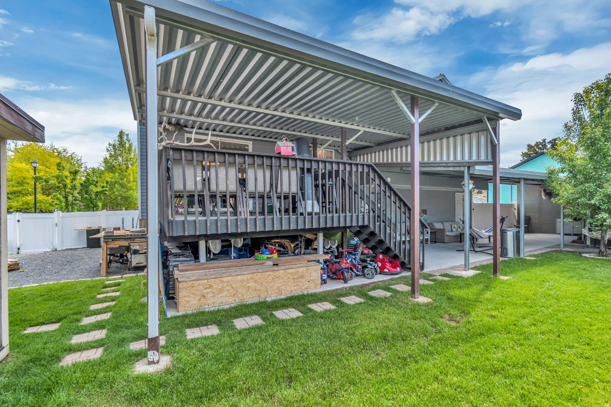 Expansive outdoor living area featuring a covered deck, lower patio space, and a manicured lawn