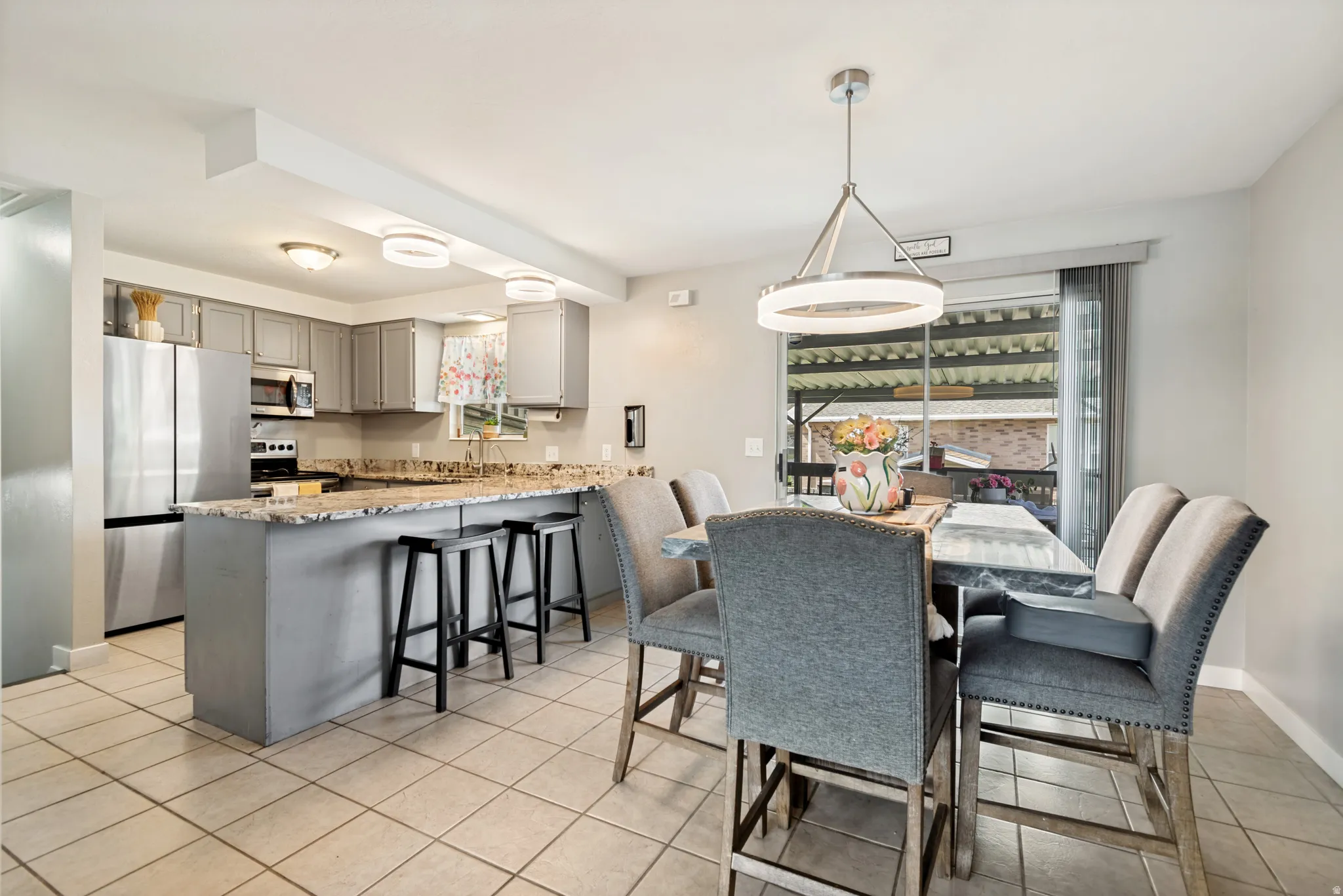 Open-concept kitchen and dining area featuring a breakfast bar with seating, stainless steel appliances, and a sliding glass door