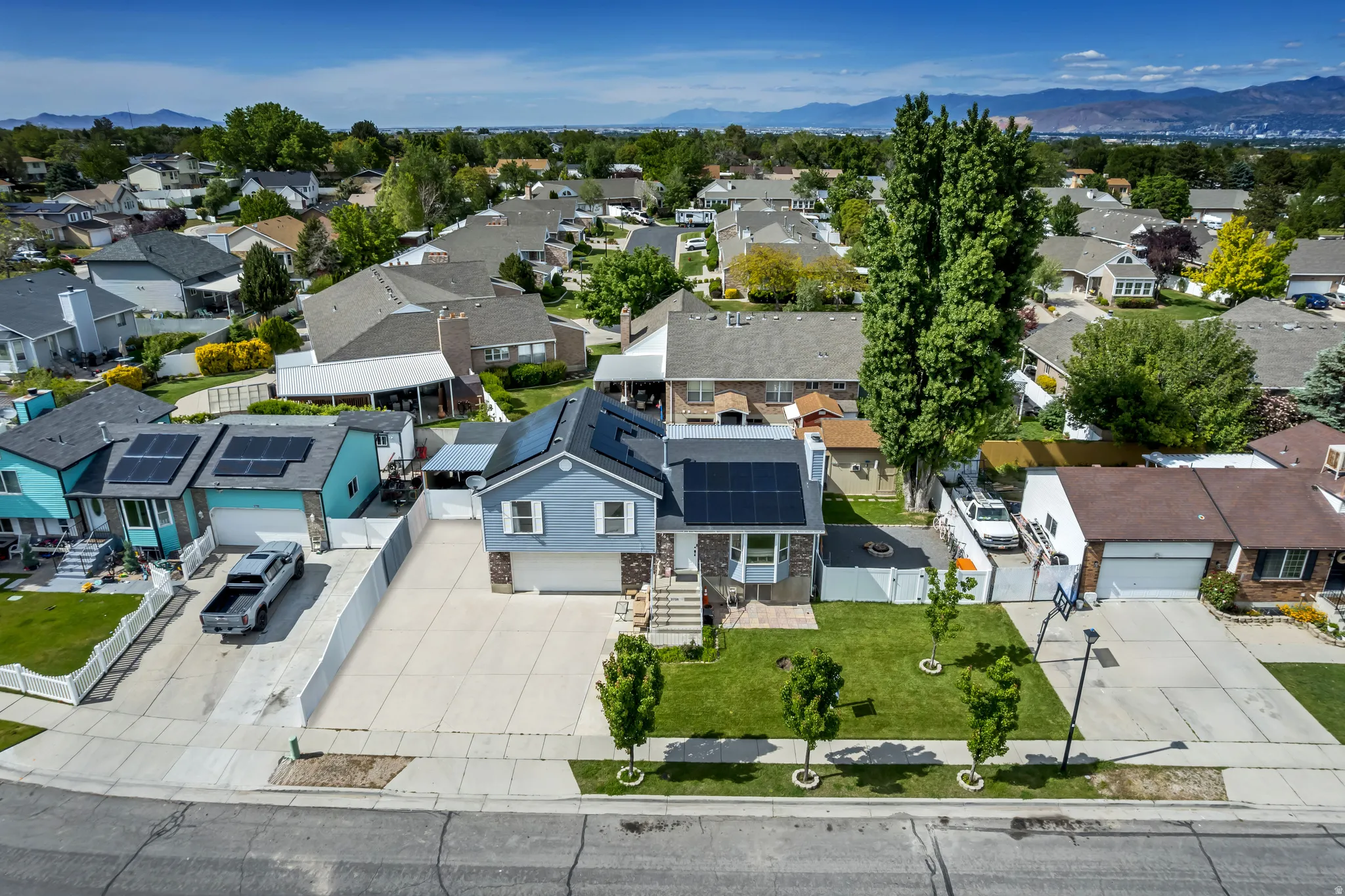 Two-story residence featuring light blue siding, white window trim, and a dark shingle roof with visible solar panels