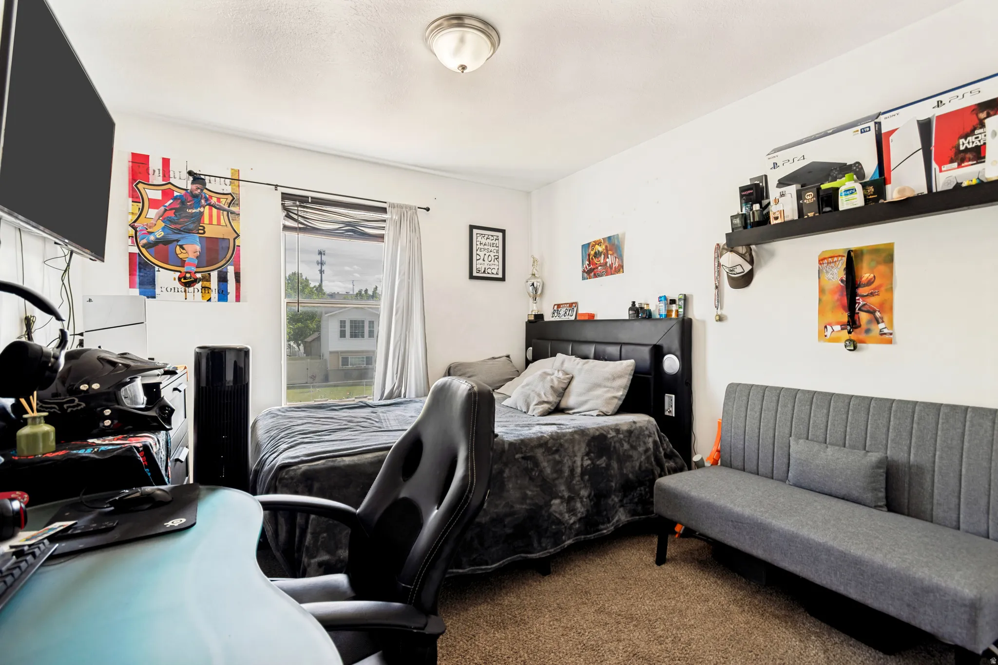 Carpeted room featuring a window with a curtain rod, a ceiling-mounted light fixture, a wall-mounted shelving unit, and a built-in headboard
