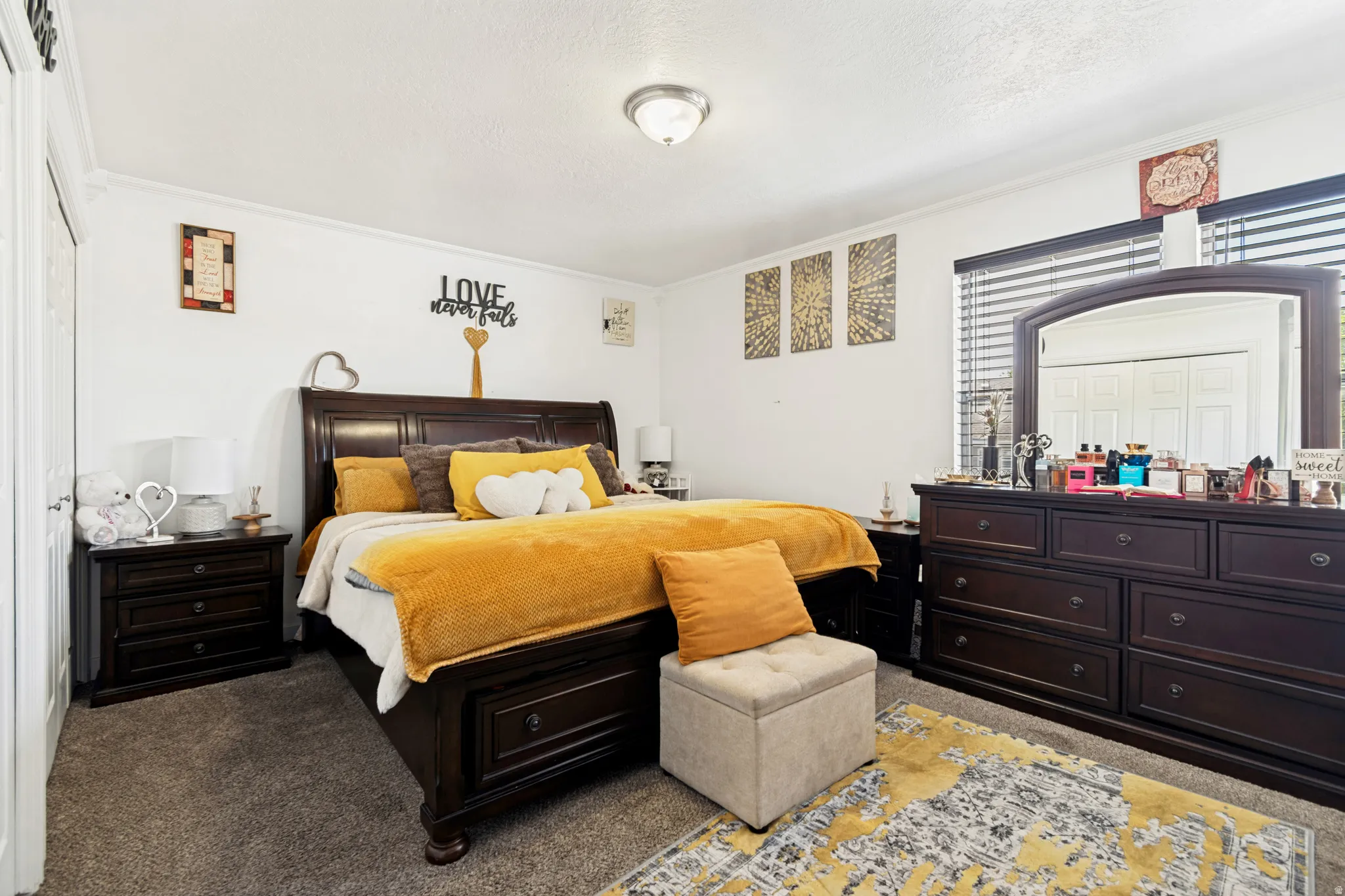 Carpeted bedroom featuring a window with horizontal blinds, a ceiling-mounted light fixture, and crown molding