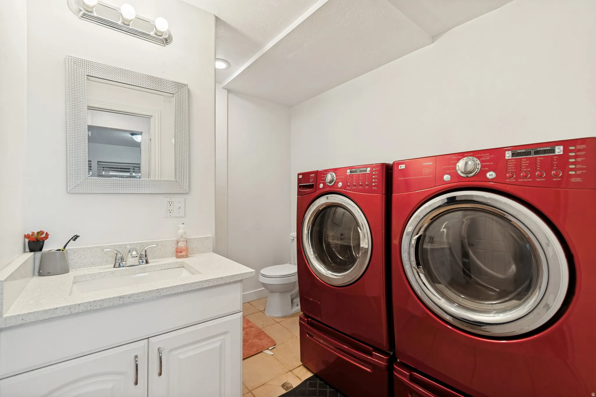 Well-appointed utility area featuring a white vanity with an integrated sink, a speckled countertop, and a chrome faucet