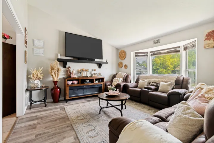 Living area featuring wood-finish flooring, a contemporary electric fireplace with media console, and a wall-mounted display shelf