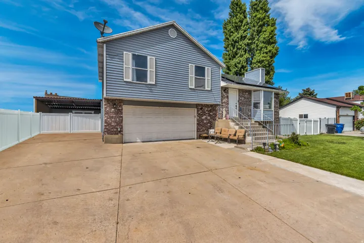 Split-level residence featuring a two-car garage, partial brick and horizontal siding exterior, and a concrete driveway