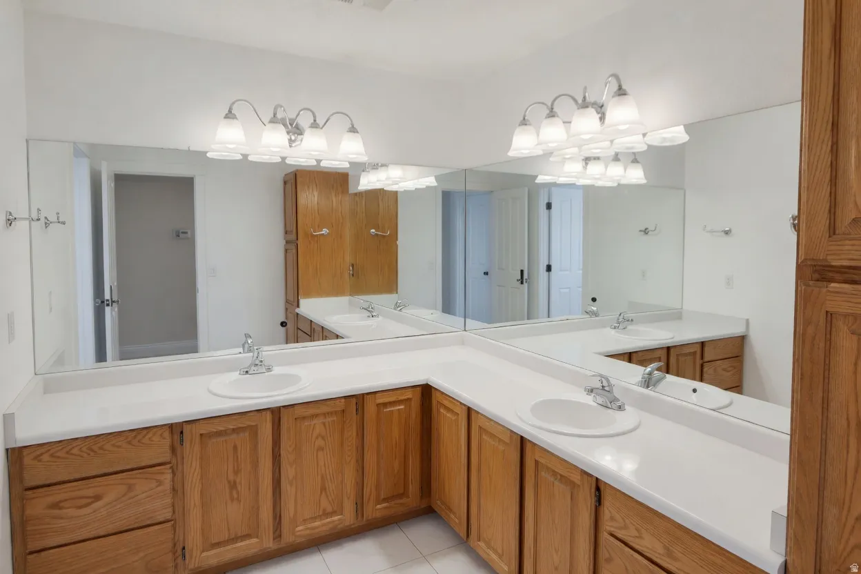 2nd bathroom on upper floor, seperate from bath/shower/toilet. Featuring a dual vanity with white countertops and wood cabinetry