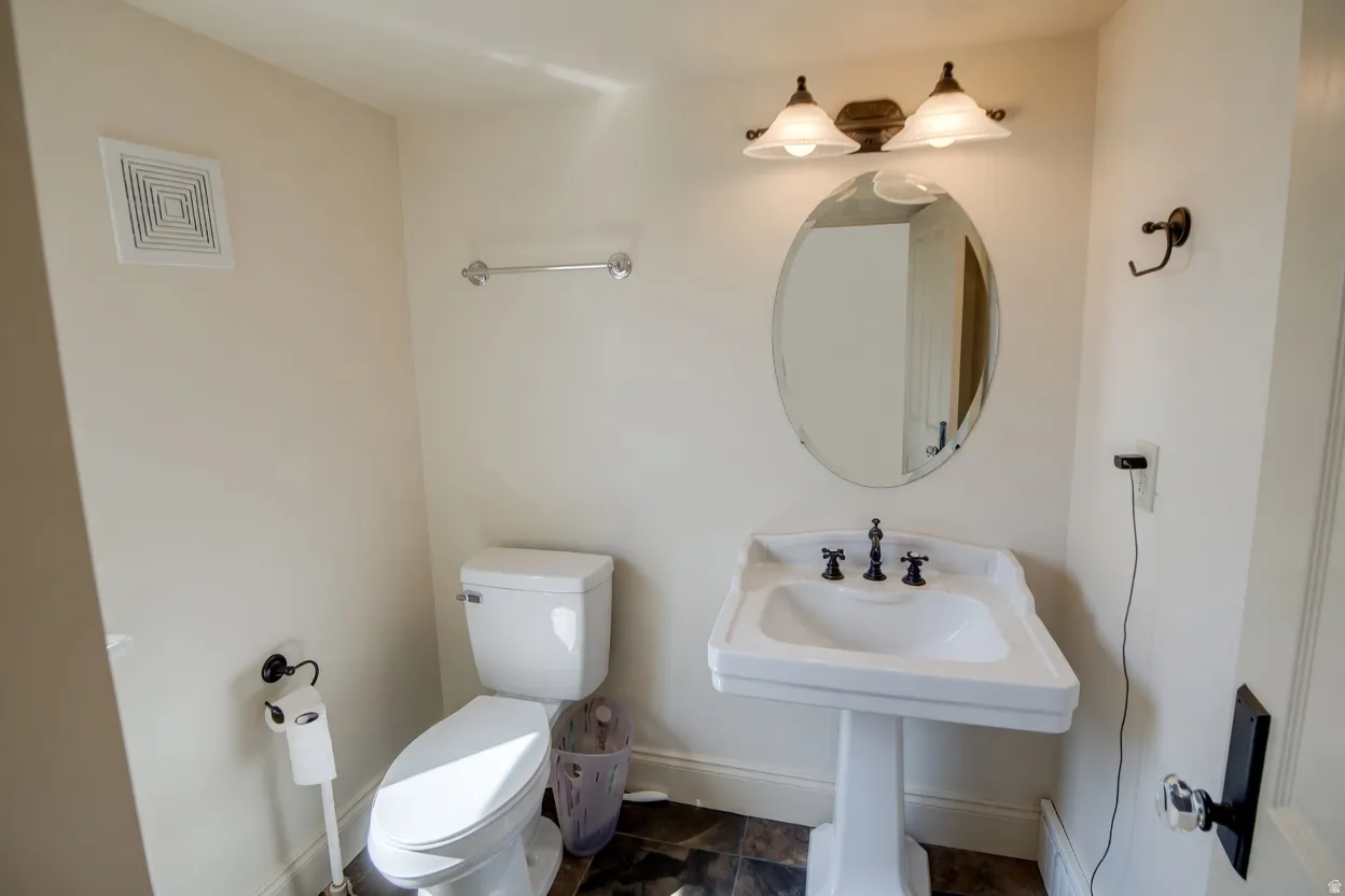 Pedestal sink with black-finish fixtures, complemented by an oval mirror and a two-light vanity fixture
