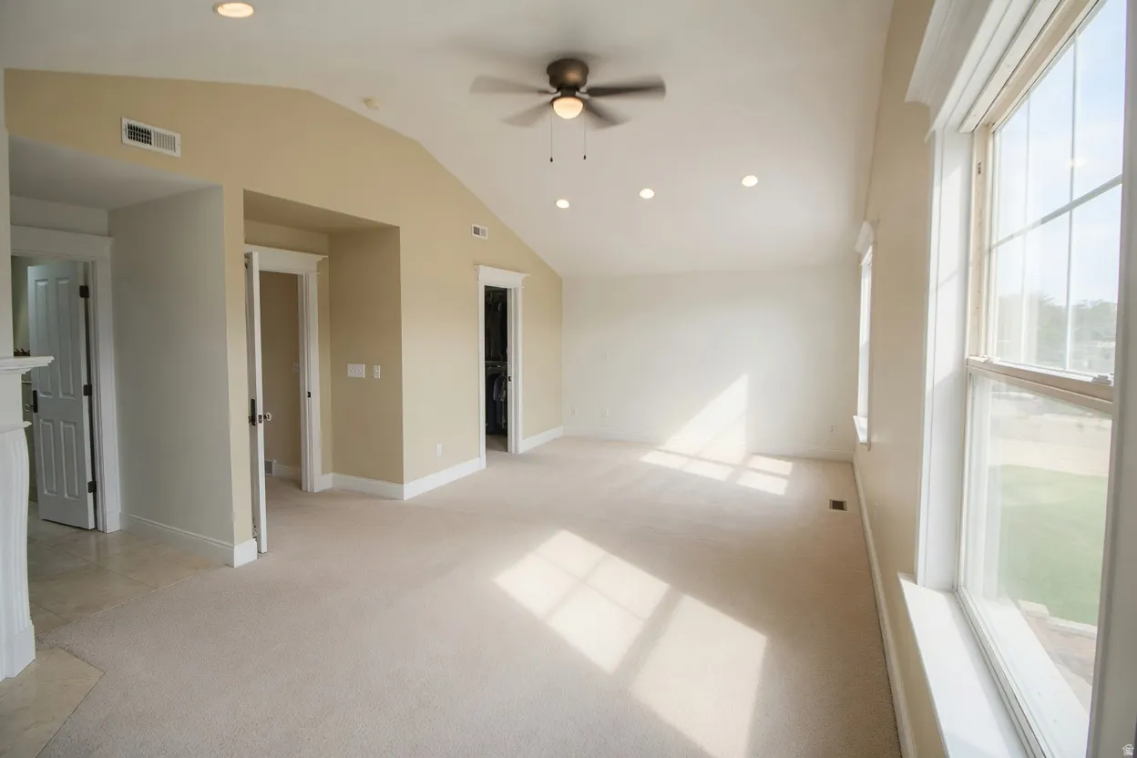 Spacious Master bedroom with vaulted ceilings, recessed lighting, a ceiling fan, and large windows providing abundant natural light