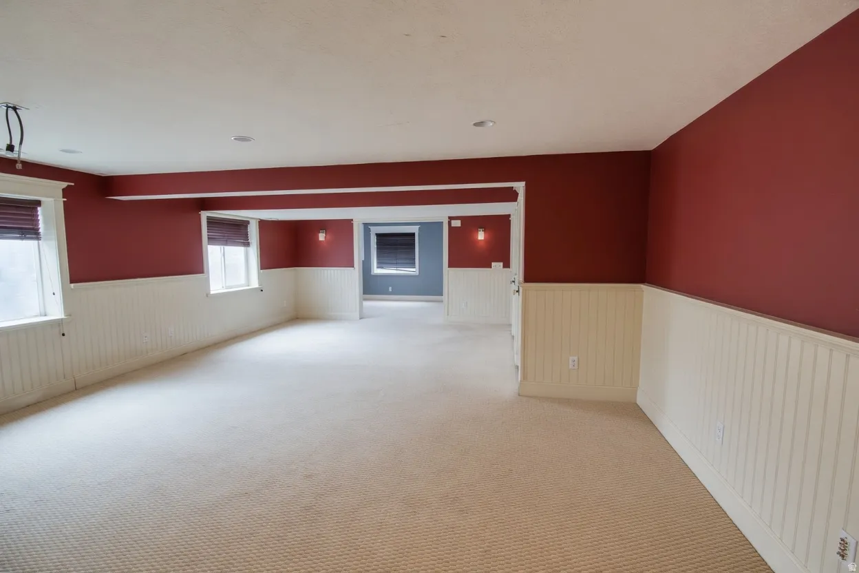 Spacious room featuring cream-colored carpeting, white beadboard wainscoting, and deep red walls