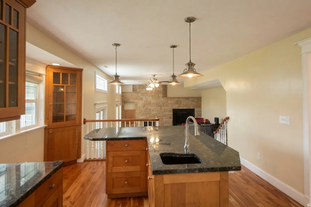 Kitchen island featuring a dark composite sink, gooseneck faucet, and dark granite-finish countertop, showing the large room attached for entertaining.