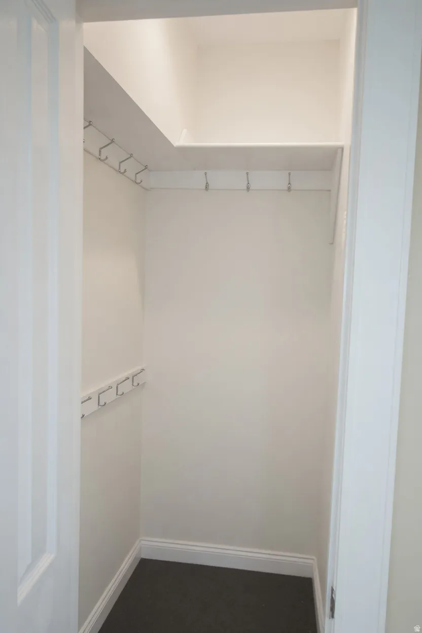 Bedroom 4 or nursery with compact closet space featuring white walls, dark carpet flooring, and white baseboards