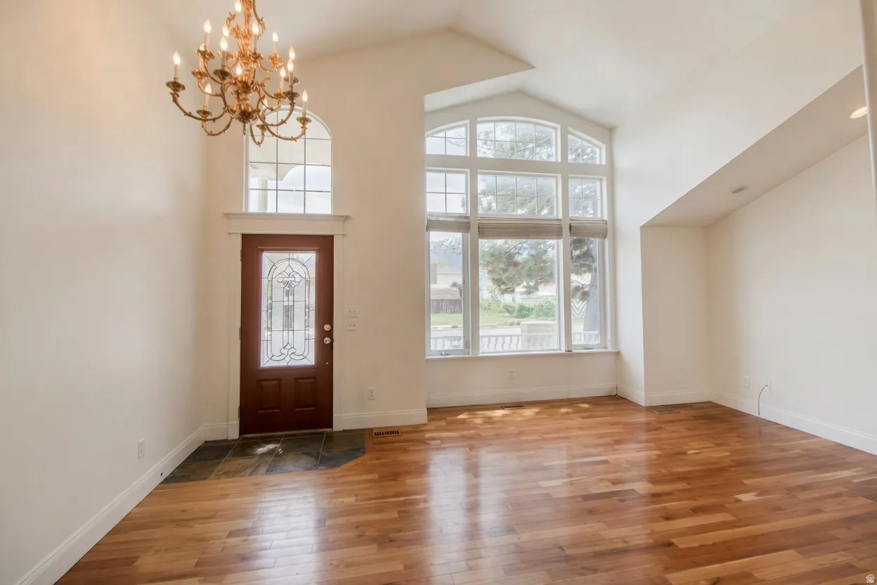 Formal living room/entry featuring a decorative glass-paneled entry door, arched transom window, and a bronze chandelier