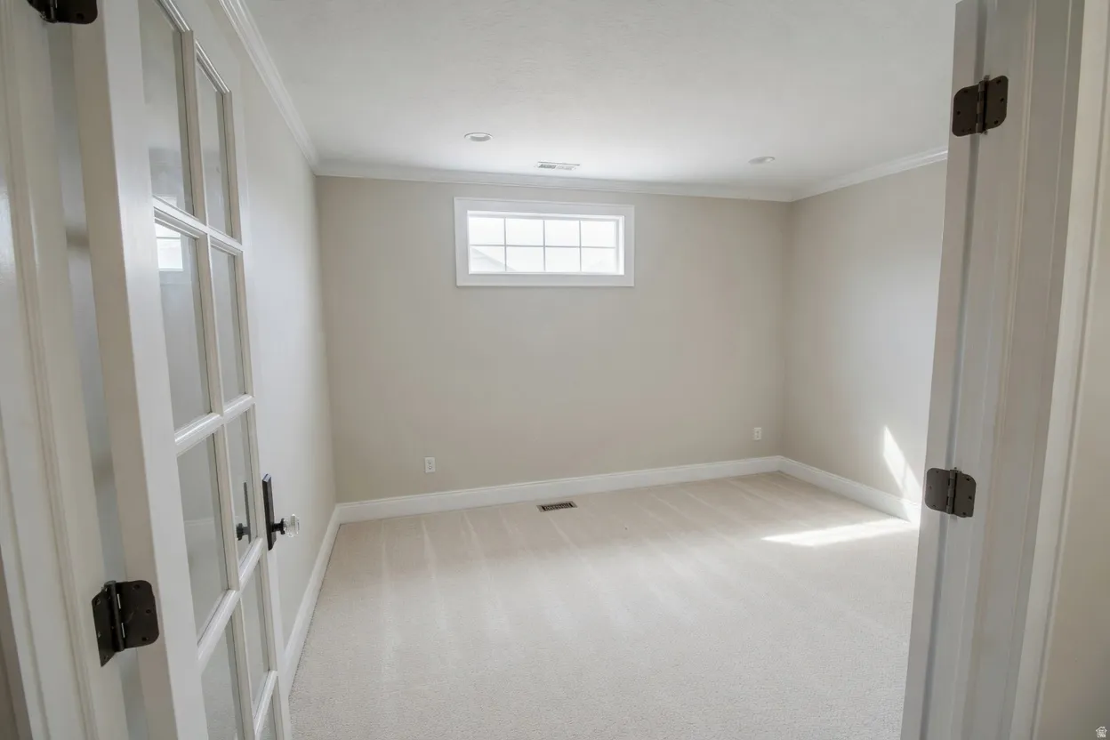 Room featuring French doors with clear glass panes, neutral-toned carpeting, a horizontal window with gridded panes, crown molding, and recessed lighting,  Can be bedroom or office.