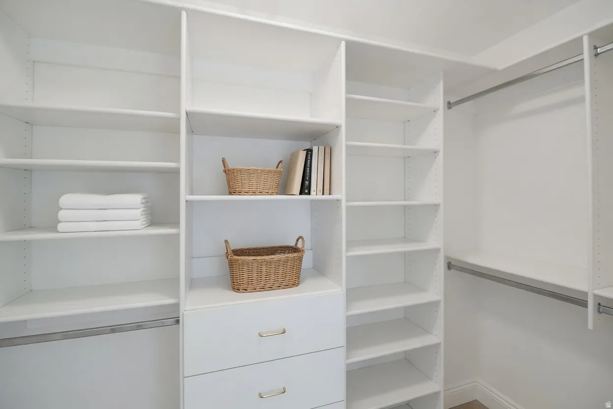 Master closet featuring multiple shelving units, integrated drawers with gold-toned hardware, and chrome hanging rods
