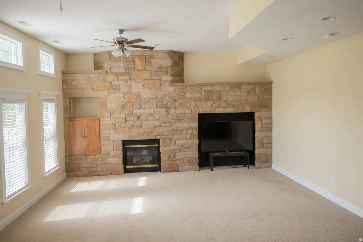 Spacious room featuring a stacked stone accent wall with a built-in fireplace and integrated media niche