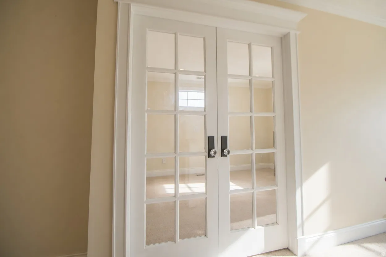 French doors with clear glass panes and black hardware, can be bedroom or office.