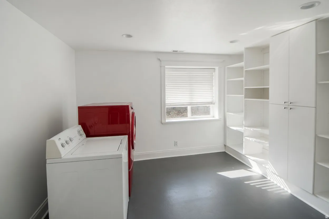 Bright utility space featuring recessed lighting, a window with blinds, and extensive built-in white shelving and cabinetry for storage