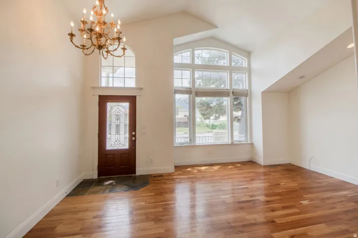 Formal living room/entry featuring a decorative glass-paneled entry door, arched transom window, and a bronze chandelier