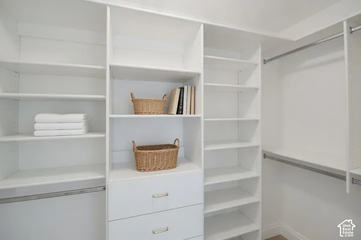 Master closet featuring multiple shelving units, integrated drawers with gold-toned hardware, and chrome hanging rods