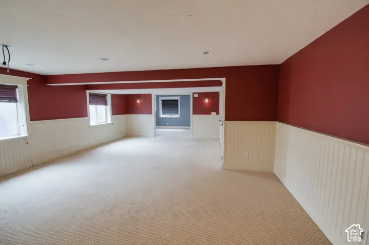 Spacious room featuring cream-colored carpeting, white beadboard wainscoting, and deep red walls