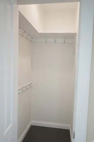Bedroom 4 or nursery with compact closet space featuring white walls, dark carpet flooring, and white baseboards