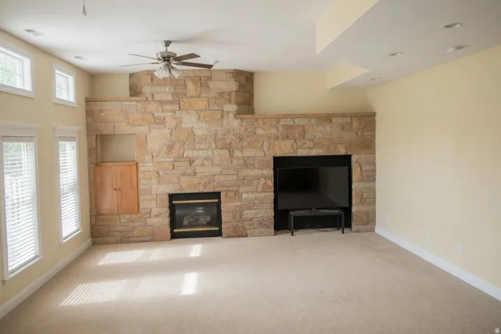 Spacious room featuring a stacked stone accent wall with a built-in fireplace and integrated media niche