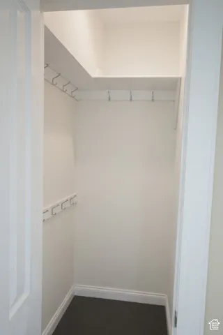 Bedroom 4 or nursery with compact closet space featuring white walls, dark carpet flooring, and white baseboards