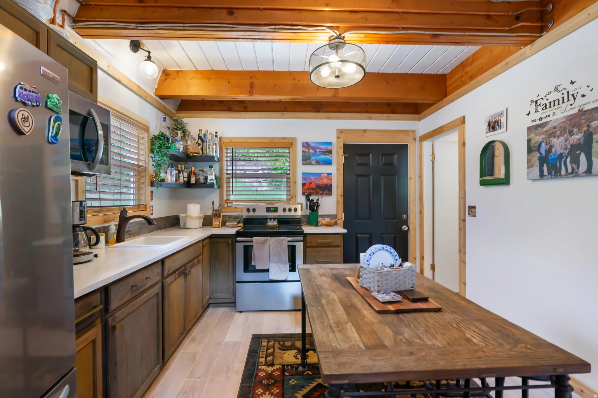 Kitchen featuring wood-finish cabinetry, stainless steel appliances, white countertops, and wood-finish ceiling beams