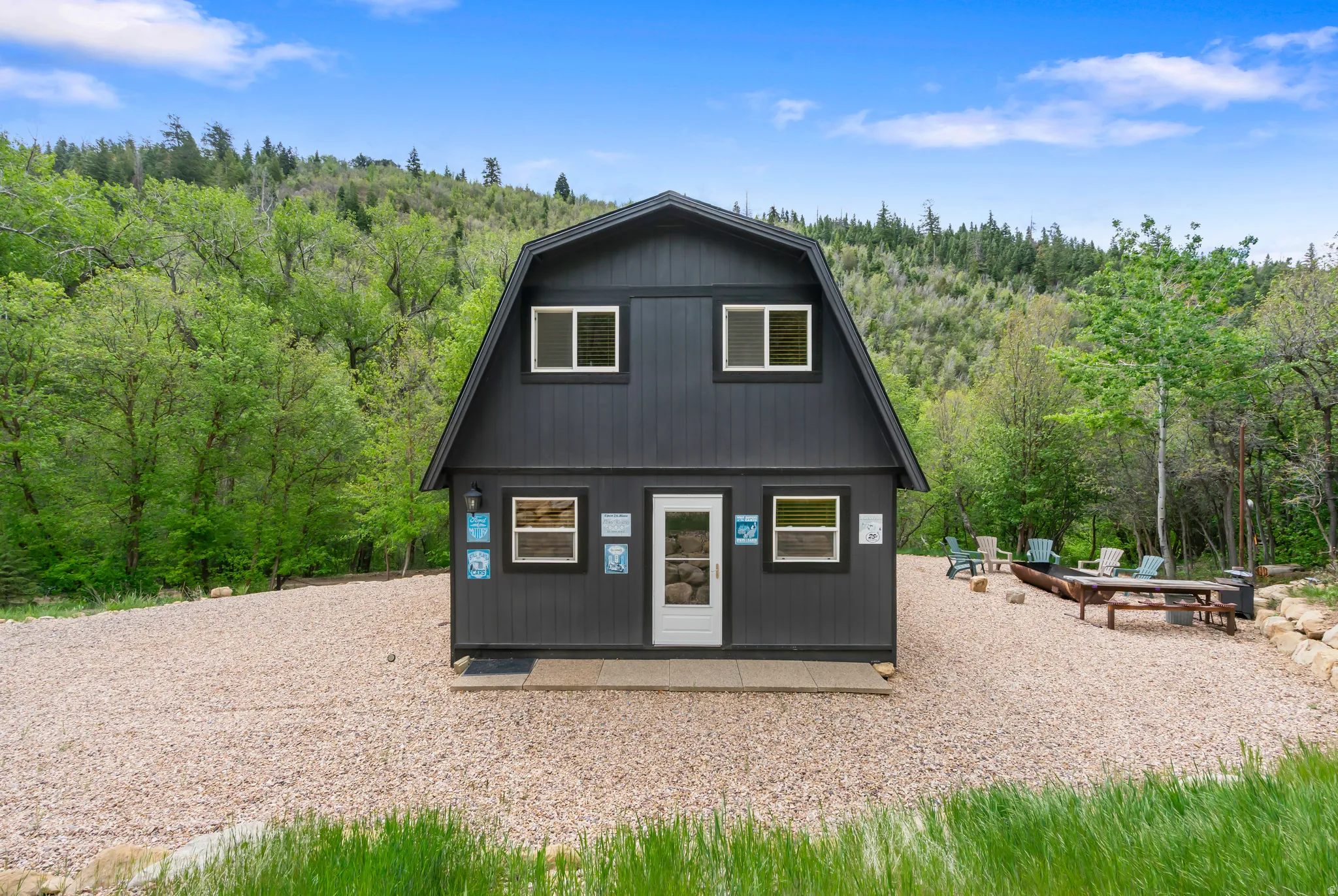 Gambrel-style residence featuring dark siding and white trim windows