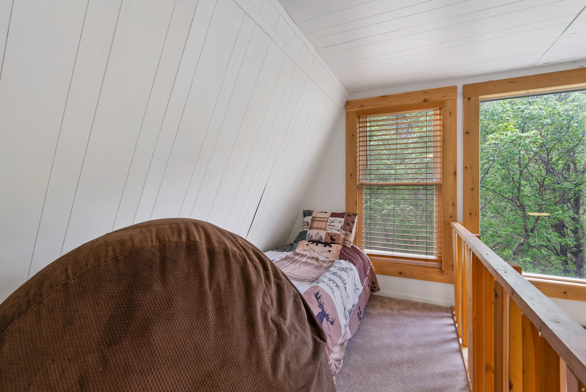 Sloped shiplap walls featuring a wood-framed window with blinds