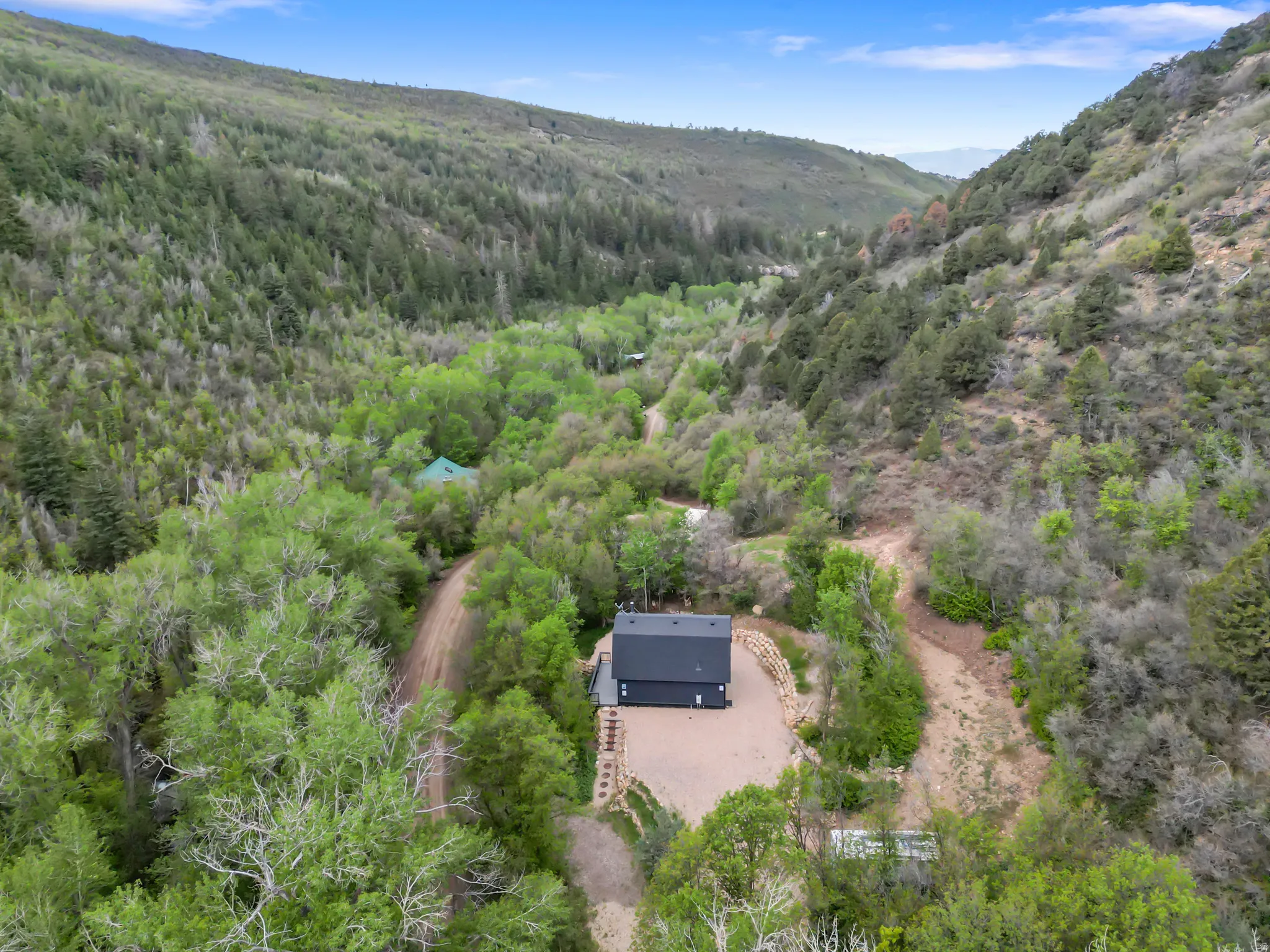 Modern-style residence situated within a lush, tree-filled valley with surrounding hillsides