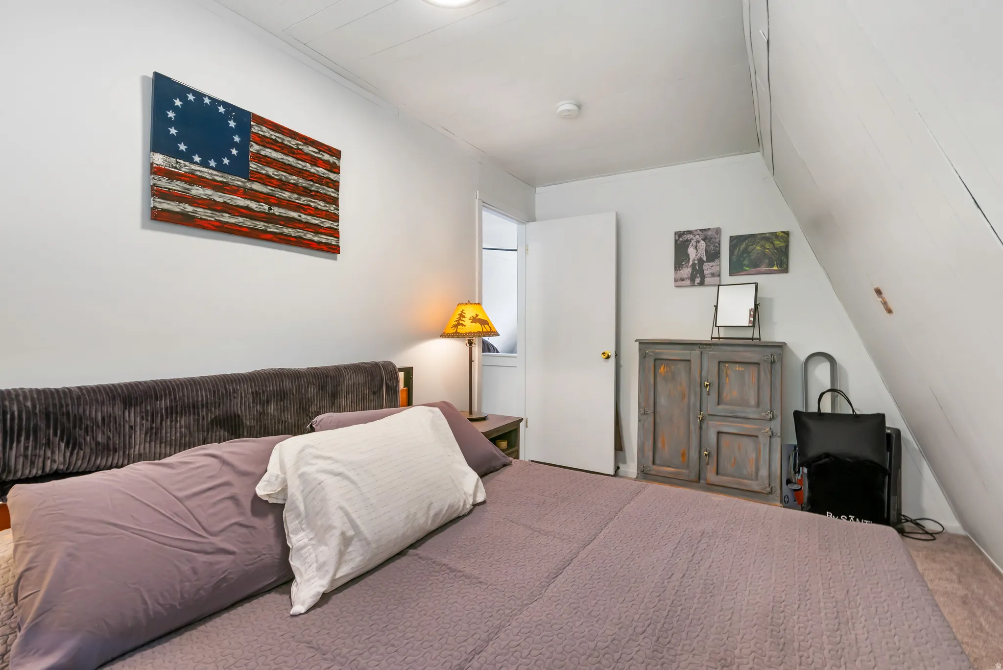 Attic room featuring bright white walls, wall-to-wall carpeting, and an angled ceiling line