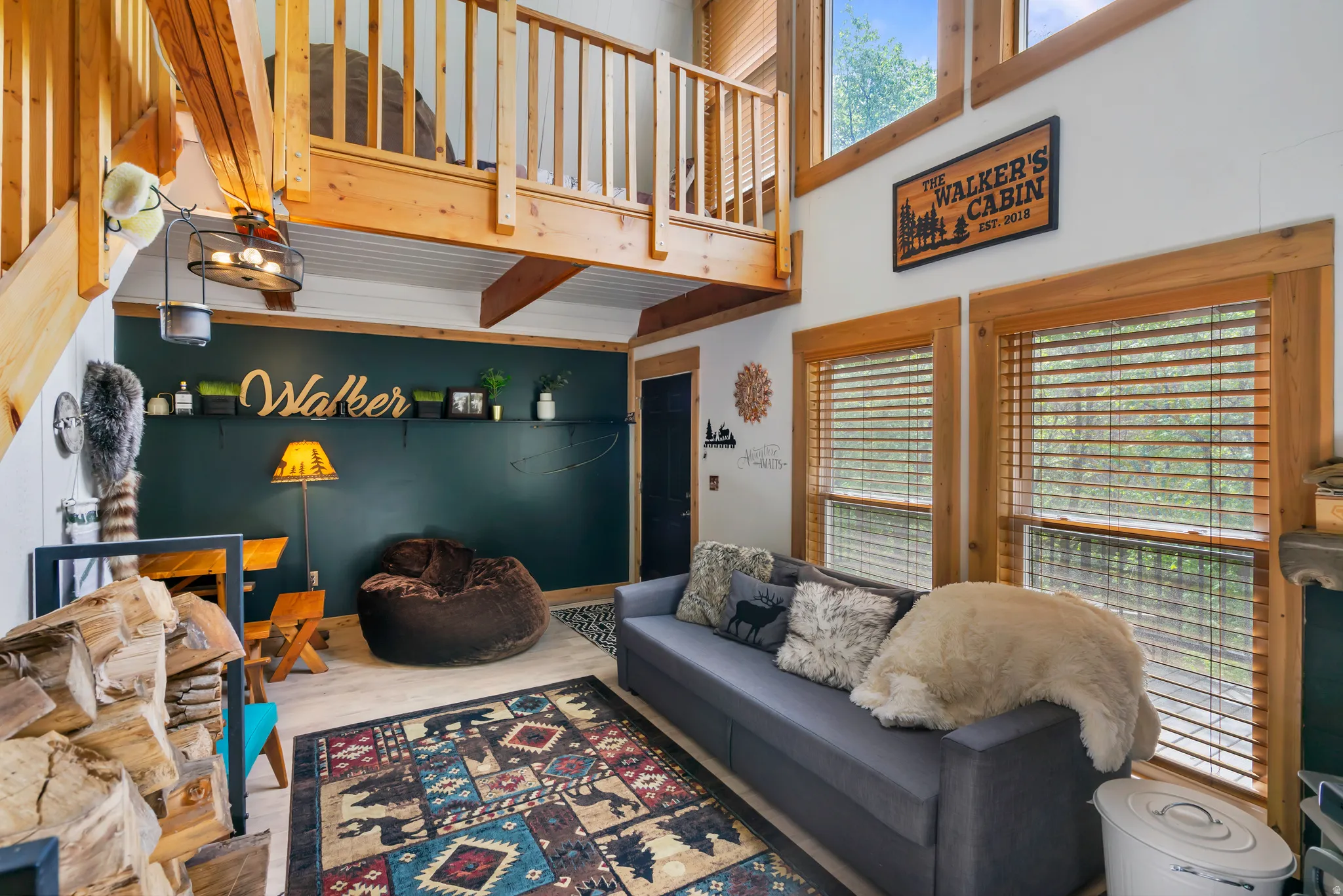 Vaulted living area featuring a loft, exposed wood beams, wood-finish flooring, and multiple windows with wood trim
