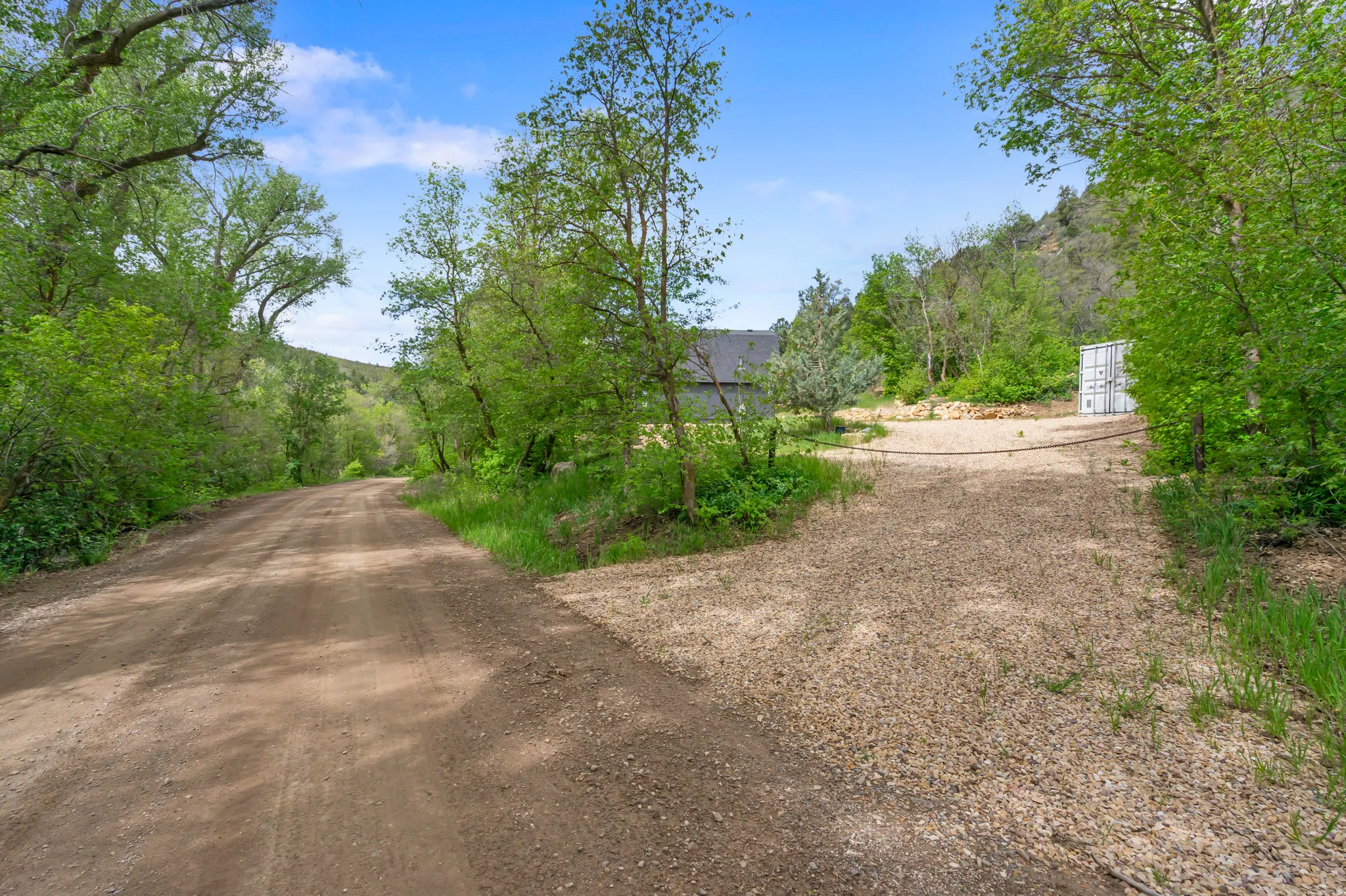 Gravel driveways leading to a property surrounded by mature trees and natural landscaping