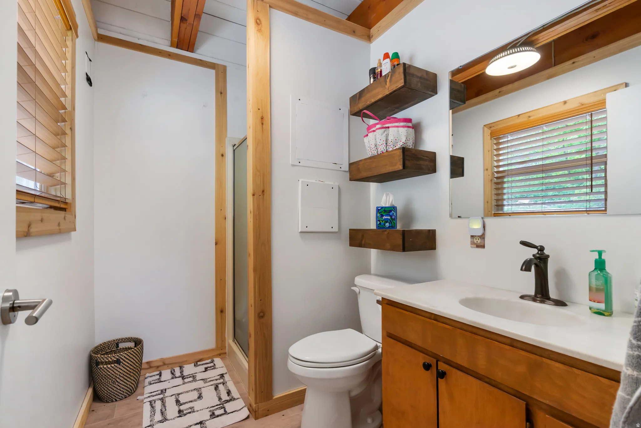 Bathroom featuring a wood-finish vanity with a single basin sink, bronze-finish faucet, and a large wall-mounted mirror