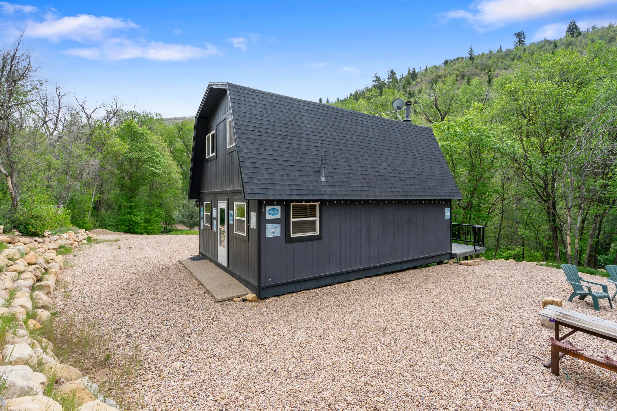 Gambrel-roof structure with dark siding and a prominent black asphalt shingle roof