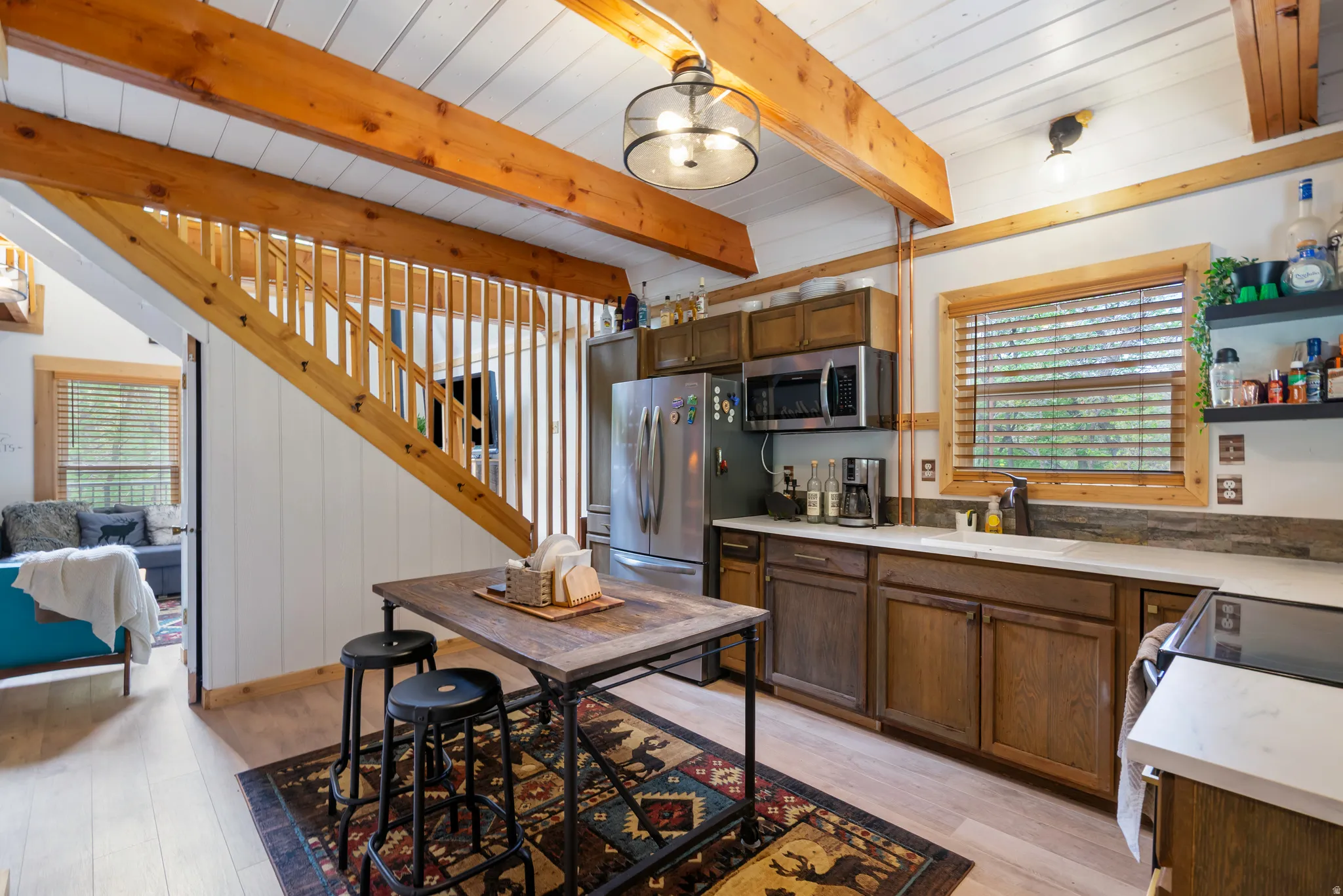 Kitchen featuring wood-finish flooring, white paneling, and exposed wood beams