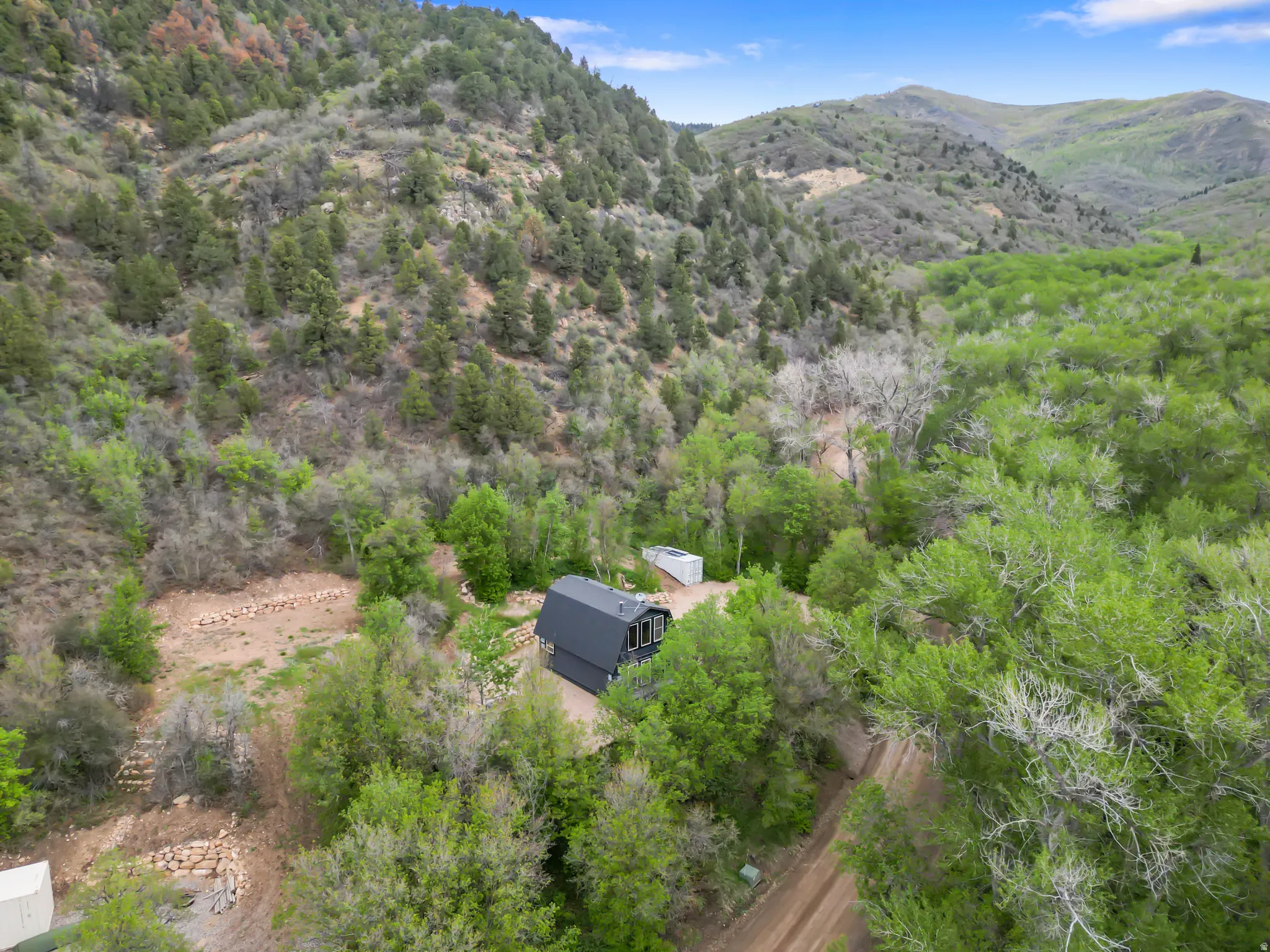 Rural property featuring a dark-toned gable roof structure and a surrounding natural landscape