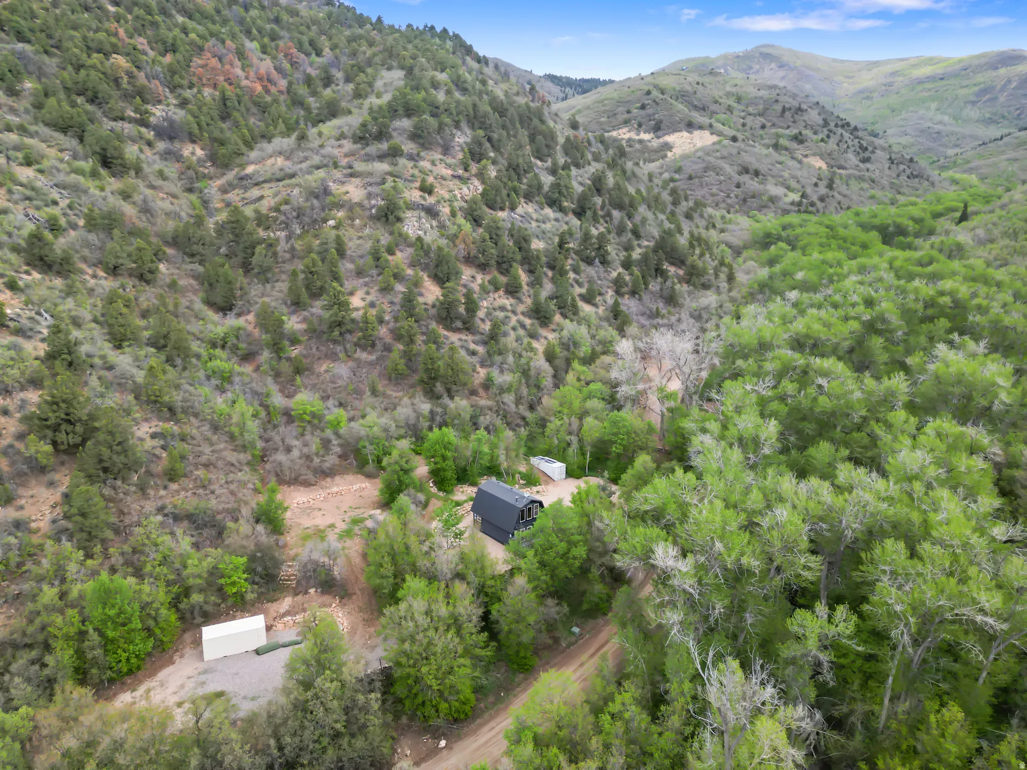Aerial perspective of a verdant mountain landscape with a contemporary barn-style structure and an additional outbuilding