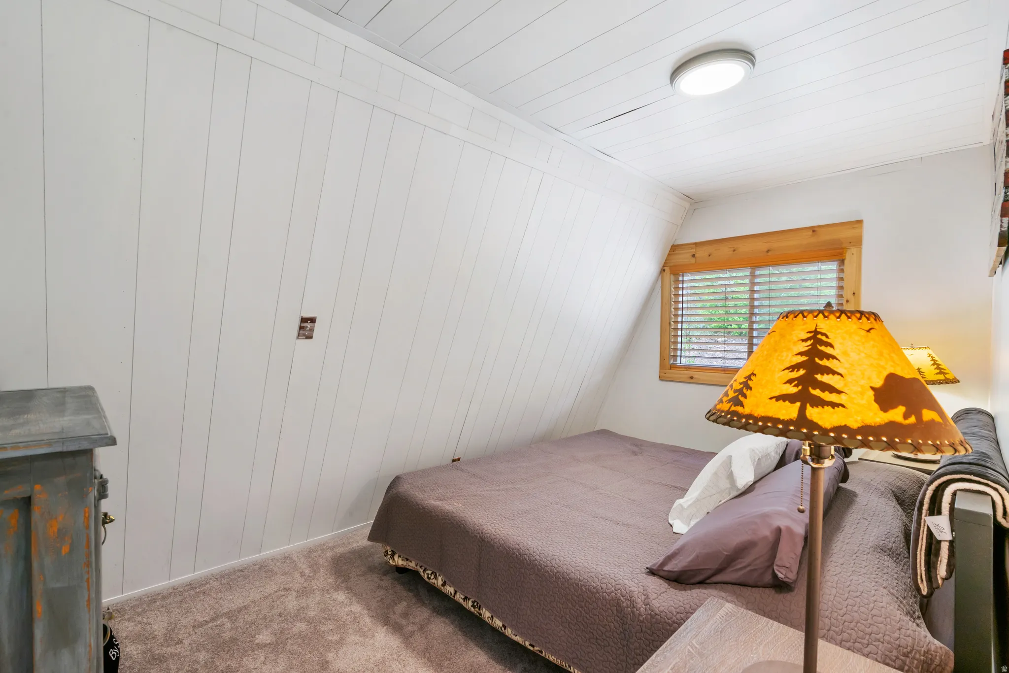 Bedroom featuring white plank walls, wood-finish window trim, and a flush-mount ceiling light