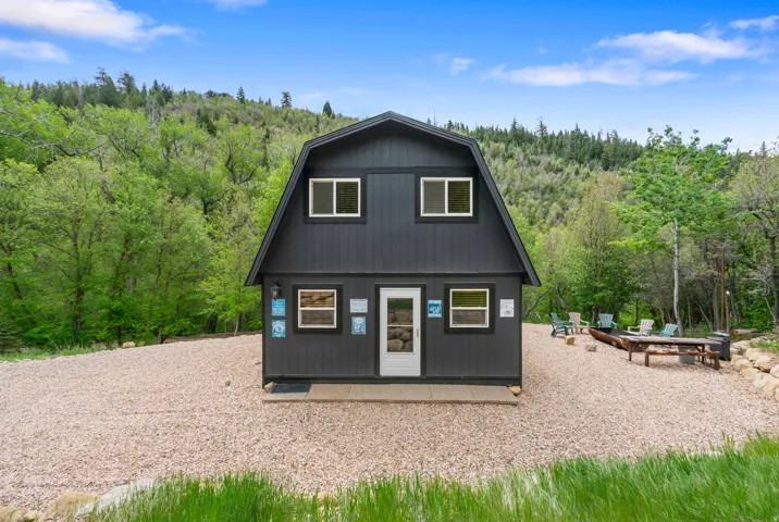Gambrel-style residence featuring dark siding and white trim windows