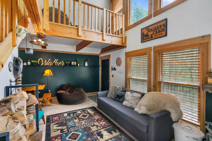 Vaulted living area featuring a loft, exposed wood beams, wood-finish flooring, and multiple windows with wood trim