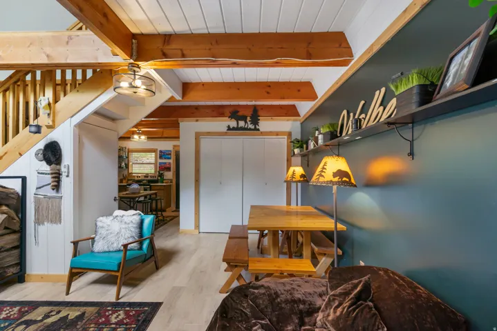 Open-concept living space featuring exposed wood beams and light wood-finish flooring