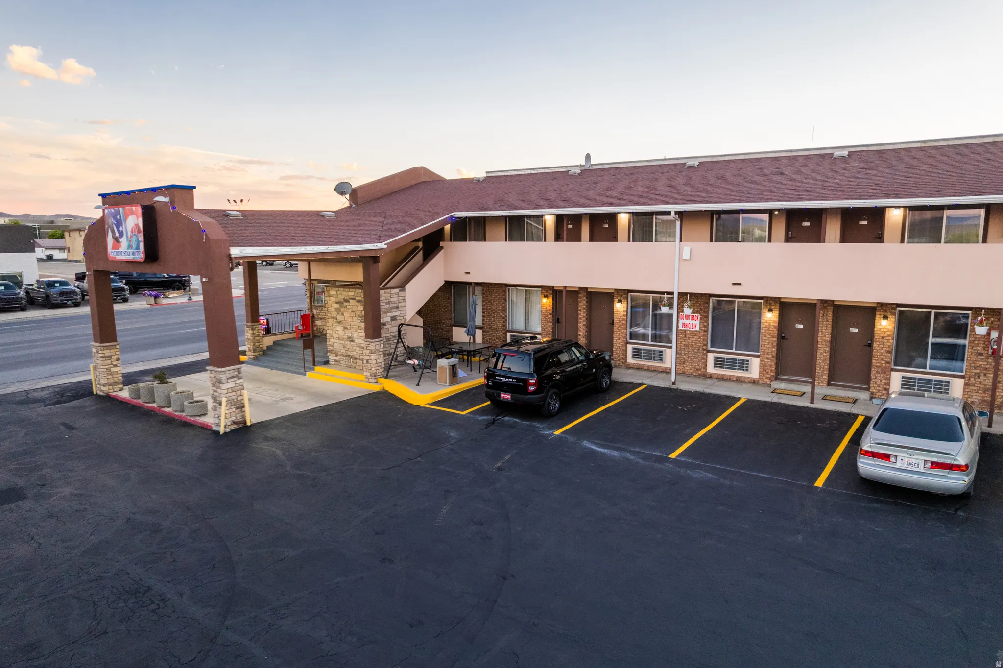 Multi-story building featuring a brown shingle roof, stone veneer accents, and stucco siding