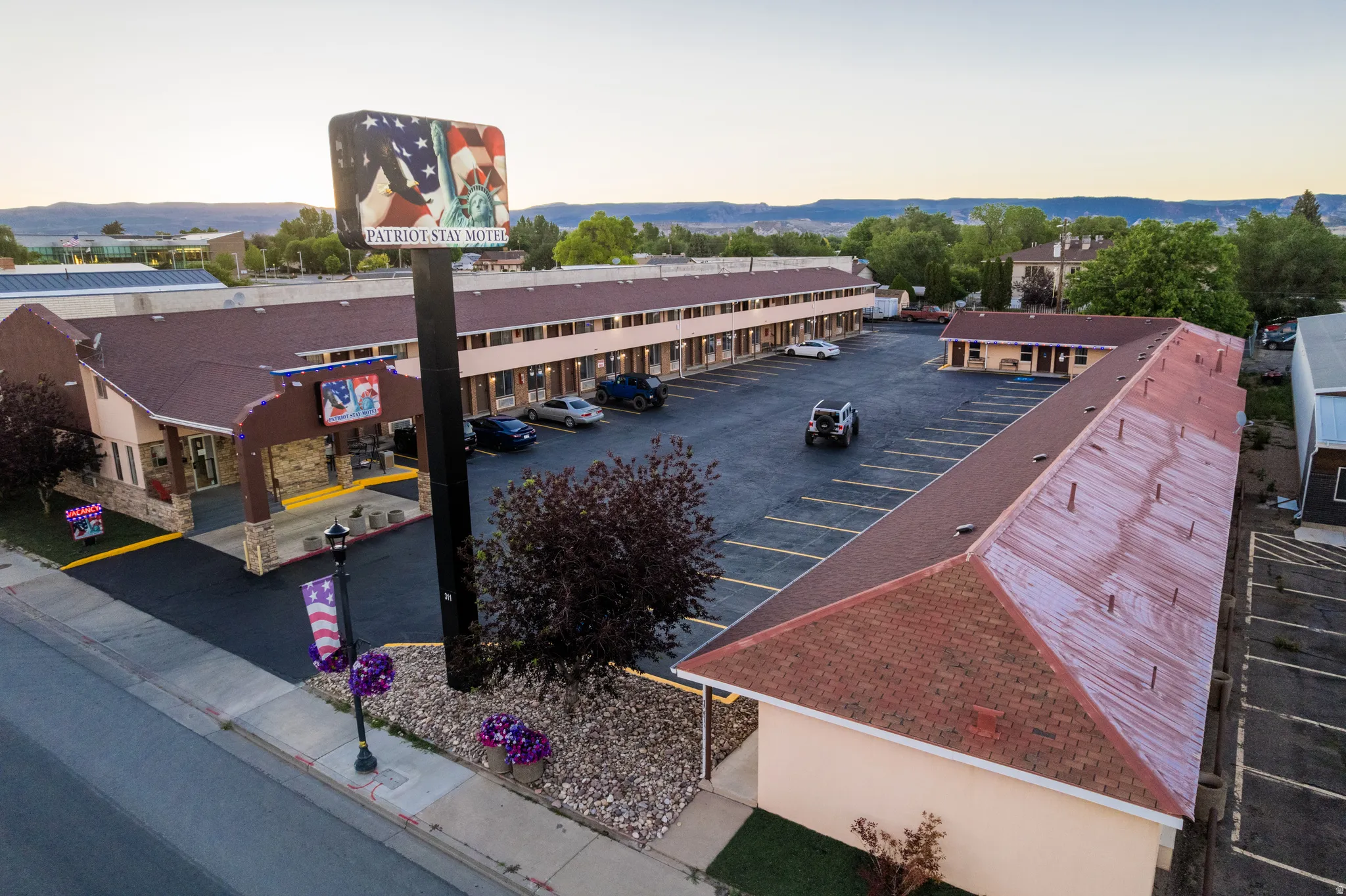 Expansive commercial property featuring multiple building structures with red tile roofing and a large asphalt parking area